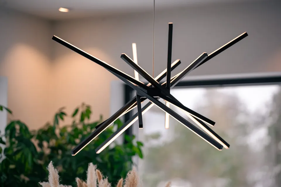 Moderne taklampe med lysende staver over en stue